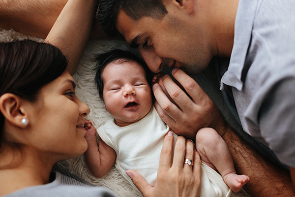 happy couple lying on floor with baby