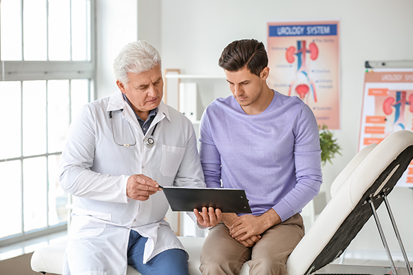 Physician talking with male patient, both looking at touchscreen pc